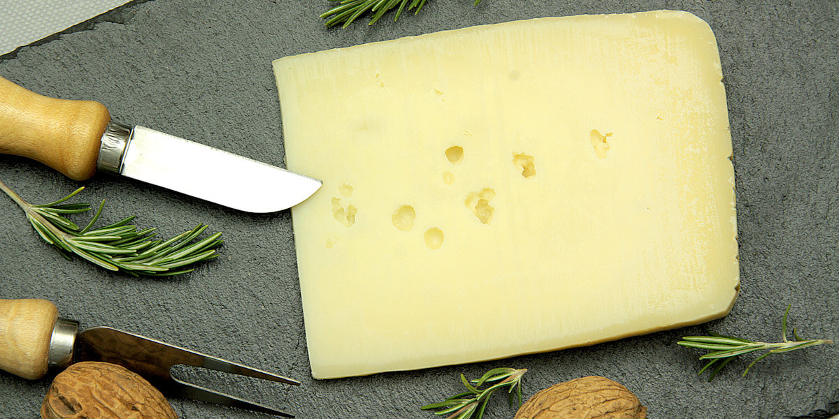 Fresh Asiago cheese on a cutting board.